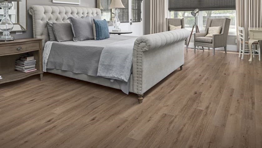 Wide-plank wire-brushed natural oak engineered hardwood in a primary bedroom suite