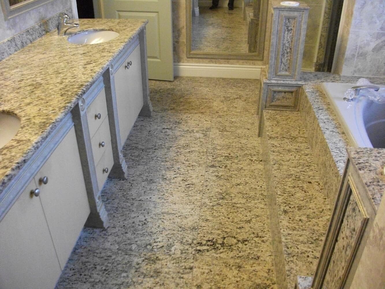 Polished granite floor tiles and matching stone bathtub deck surround in a luxury ensuite