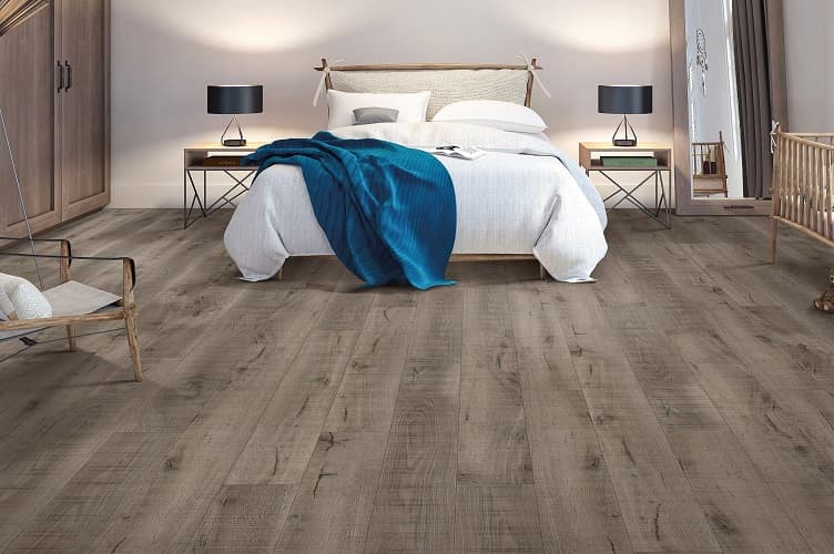 Weathered greige oak embossed laminate planks installed across a bright bedroom
