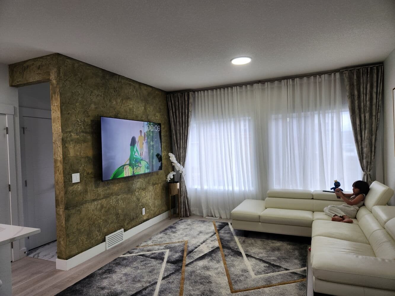 Floor-to-Ceiling Wave Sheer Curtains & Drapery Panels - Window Coverings by Deluxe in Toronto Residence. Architectural ceiling-recessed ripplefold sheer curtains paired with tailored drapery side panels, flanking an Aris Stone textured feature wall.