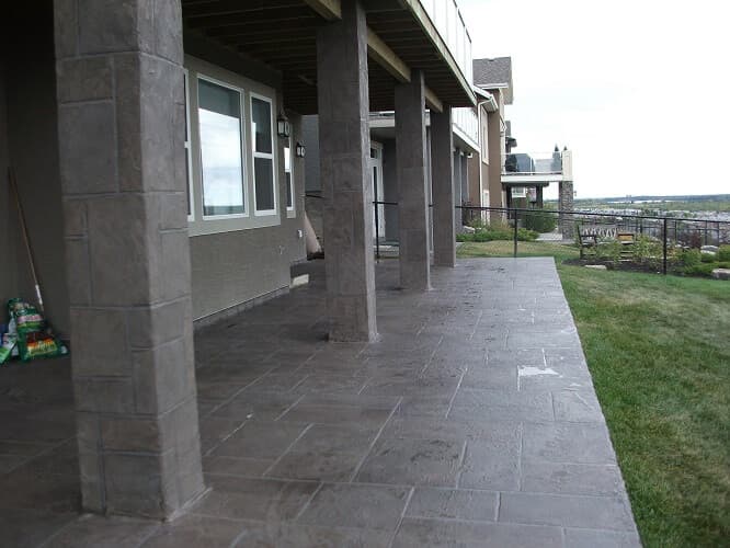 Aris Stone covered walkout patio with textured stone-clad foundation pillars
