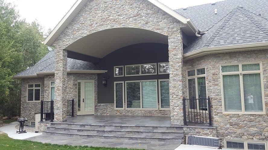 Luxury Calgary estate featuring custom Aris Stone covered patio, tiered steps, and stone facade