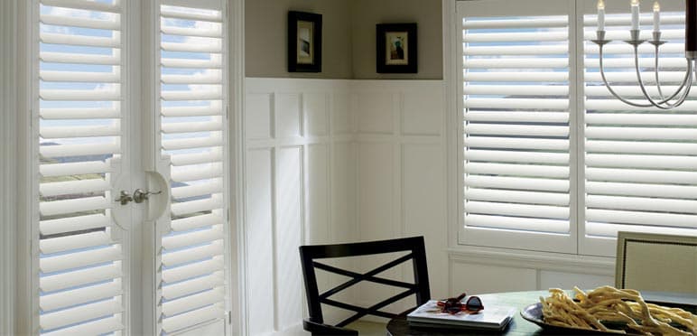 Full-height white louvred shutters complementing traditional dining room wainscoting